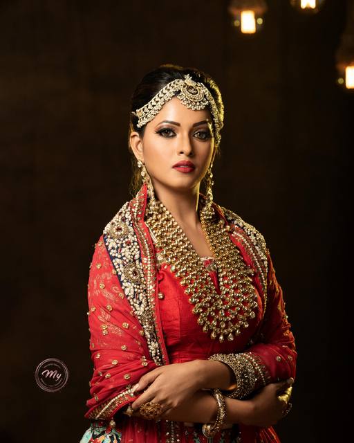 Studio bridal portrait in red with layered kundan jewellery and a bold red lip