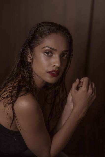 Low-key moody portrait with wet-look hair and a deep red lip